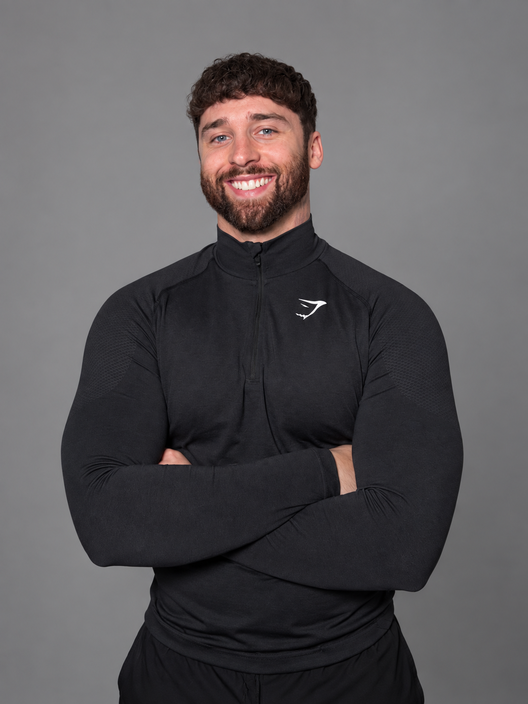 Harry Kaye, smiling with arms crossed in a black training top
